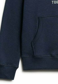 Marineblauwe sweater met een voorzak, ribgebreide boordjes en zoom. Zachte stof; heeft bedrukte tekst in een lichtere kleur.