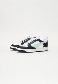 Baskets noir et blanc avec des accents vert menthe, présentant une texture en cuir lisse, une boîte à orteils perforée et des lacets blancs plats.