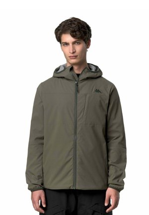 Giovane uomo che indossa una giacca con cappuccio verde oliva con cerniera frontale e tasca al petto, in piedi contro uno sfondo bianco.