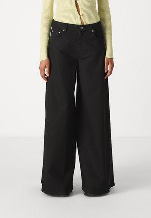 Pantaloni neri a gamba larga realizzati in denim, con vita alta, tasche anteriori e dettagli in metallo argentato. Tessuto morbido con una vestibilità ampia.