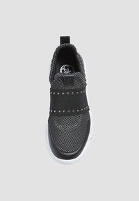 Baskets à enfiler noires et blanches avec dessus en maille texturée, bande élastique cloutée sur le milieu du pied, et semelle en caoutchouc blanche.