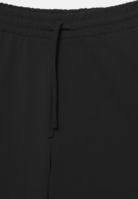 I pantaloni della tuta neri presentano una cintura elastica con coulisse, realizzati in un tessuto morbido con una texture liscia e senza motivi visibili.