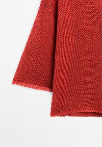 Rode gebreide trui met een open geweven textuur, met losse mouwen en een zoom met een gekartelde rand.