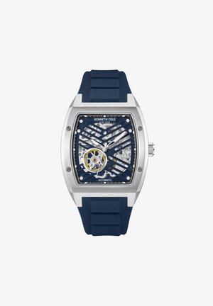Blå silikonestrapsur med et sølvfarvet rustfrit stål urkasse, åben dial og intrikat mekanisk bevægelse. Har Kenneth Cole branding.