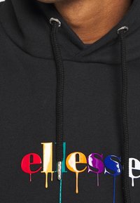 Sweat à capuche noir avec un logo coloré effet peinture qui coule. Comprend des cordons de serrage avec des accents métalliques et une texture douce.