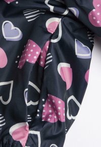 Tissu coloré avec un fond sombre présentant des cœurs roses et violets, des pois et des motifs rayés ; texture lisse, léger.