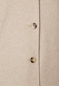 Beige wolblend jas met een zachte textuur, een enkel-breasted ontwerp en twee grote, ronde, gemarmerde knopen.