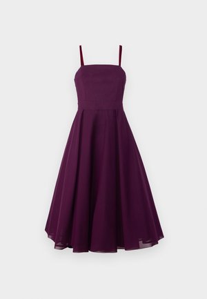 Un vestito senza maniche, lungo fino al ginocchio, di un profondo colore viola, con un corpetto aderente, gonna svasata e sottili spalline regolabili. Tessuto dalla superficie liscia.