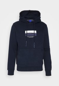 Felpa blu navy con cappuccio regolabile, tasca frontale a marsupio e patch con logo grafico. Materiale morbido con polsini e orlo a costine.