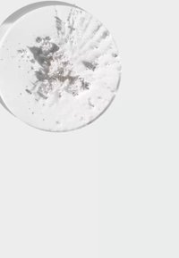 Compact rotondo di polvere bianca con superficie texturizzata, che mostra polvere bianca fine sparsa all'interno, su uno sfondo grigio chiaro.