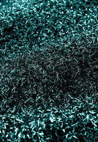 Fili metallici verdi densi e compatti, che creano una superficie riflettente e texturizzata. Il materiale sembra fine ed allungato, assomigliando a fibre.
