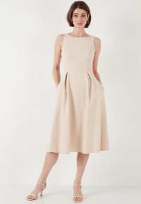 Beige midi šaty bez rukávů s přiléhavou tělem, skládáním sukně, bočními kapsami a hladkým povrchem. Mají kulatý výstřih a minimalistický design.