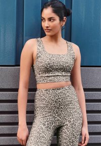 Leopardprint sportoutfit in beige en grijs, bestaande uit een crop top met vierkante halslijn en hoge taille leggings met een soepele textuur.