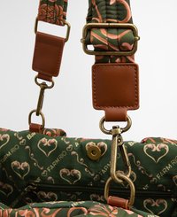 Sangle en tissu vert avec un motif floral rose, comportant des accents en cuir marron et des clips en laiton pour l'attache.