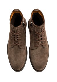 Brązowe zamszowe botki za kostkę z okrągłym noskiem, sznurowanym przodem i zamkiem błyskawicznym z boku. Wykończone gładką wyściółką i gumową podeszwą.