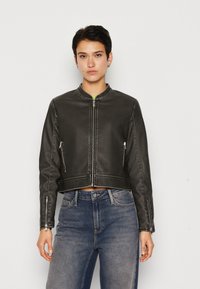Veste en cuir noir cropped avec un col rond, fermeture à glissière à l'avant et poches zippées sur les côtés. La texture est lisse avec des détails de surpiqûres contrastantes.