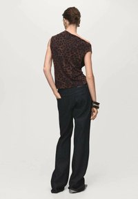 Brown leopard-print sleeveless top paired with dark wide-leg jeans, showcasing a relaxed fit and smooth fabric texture.