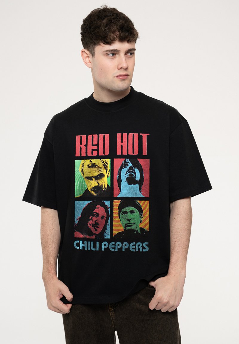 Black oversized t-shirt featuring a colorful graphic print of four band members with the text “RED HOT CHILI PEPPERS” at the bottom.