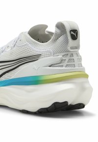 Puma løbesko har en åndbar hvid strikoverdel, sorte accenter, en flerfarvet gradiensål og en tekstureret sort gummiydersål.