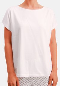 White short-sleeve top with a loose fit and round neckline, made of soft cotton fabric. Seamless edges provide a clean finish.