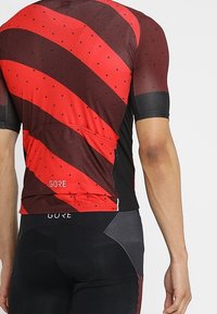 Jersey de ciclismo de manga corta con llamativas franjas rojas y negras, textura de malla, acentos reflectantes y un bolsillo trasero para almacenamiento.