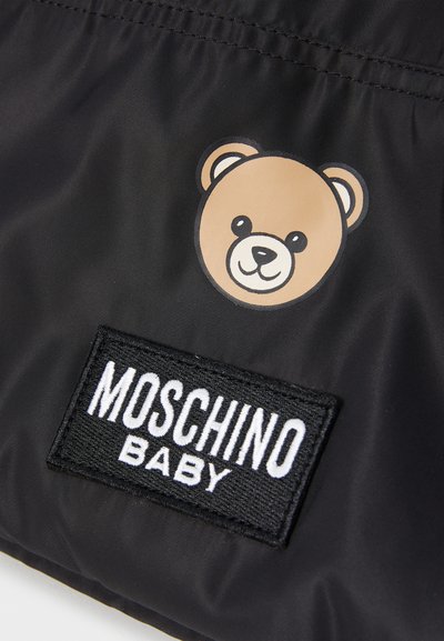 Tessuto in nylon nero con una grafica di un orso beige e un'etichetta rettangolare nera con testo bianco "MOSCHINO BABY" in basso.