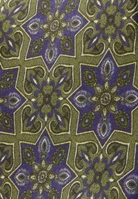 Tekstil med et symmetrisk mønster af blomster og indviklede former i olivengrøn og lilla, med detaljerede accenter og stilarter.