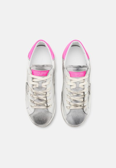 White sneakers with gray suede accents, pink heel trim, and beige laces. Features a logo on the tongue and a smooth texture throughout.