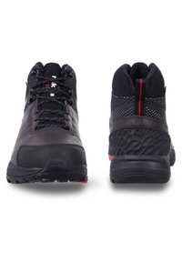 Tummanruskeat ja mustat vaelluskengät, joissa on teksturoitu kangas päällinen, punaiset yksityiskohdat ja kestävä pohja. Ominaisuuksiin kuuluu vahvistettu varvasosa ja pehmustettu säärystin.