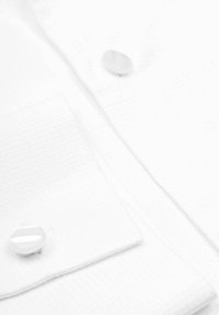 Weißes Hemd aus strukturiertem Stoff mit Karomuster, zwei runden Kunststoffknöpfen und einer einzelnen Brusttasche.