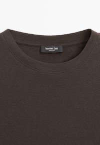 Donkerbruin T-shirt met ronde hals en een zichtbaar zwart label 'Massimo Dutti Made in China' dat aan de binnenkant van de hals is genaaid.