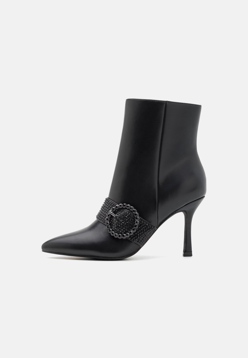 Bottine noire à bout pointu avec talon stiletto haut et bride décorative cloutée avec boucle ronde sur le côté.