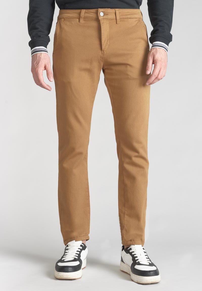 Kahlere katoenen broek met een slim fit, voorzien van een voorzak en een enkele knoopsluiting, gecombineerd met zwart-witte sneakers.