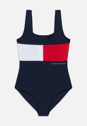 Navy one-piece swimsuit with a horizontal color block design in red, white, and navy. Logo "TOMMY HILFIGER" printed at the hip. Classic fit.