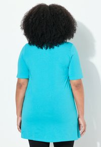 Tunique turquoise à manches courtes avec une coupe décontractée. Présente un ourlet arrondi et un tissu doux, offrant confort et aisance de mouvement.