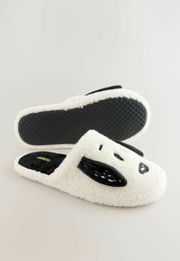 Bílé a černé plyšové pantofle s kreslenou tváří psa, textura látky a gumová podešev se zdrsněním pro lepší přilnavost.