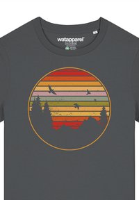 Dunkelgraues T-Shirt mit einem runden Grafikdesign, das horizontale Streifen in Rot, Orange, Gelb, Grün sowie Silhouetten von Bäumen und Vögeln zeigt.