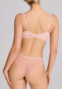 Jasnoróżowy zestaw bielizny z gładkiego materiału, z koronkowymi akcentami na ramiączkach i pasie, oraz dopasowanym krojem z regulowanymi elementami.