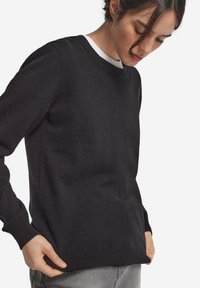 Czarny sweter wykonany z miękkiego materiału, z okrągłym dekoltem, długimi rękawami oraz ściągaczami przy mankietach i dolnym brzegu. Minimalistyczny design bez widocznych wzorów.