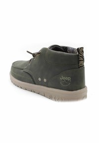 Scarpa in pelle verde con profilo basso e design con lacci. Superficie texturizzata, suola beige e fodera interna con motivo. Logo Jeep sul tallone.
