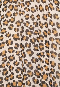 Tissu imprimé léopard présentant des taches irrégulières de marron et de beige clair sur un fond beige clair. La texture est lisse avec une apparence fluide.