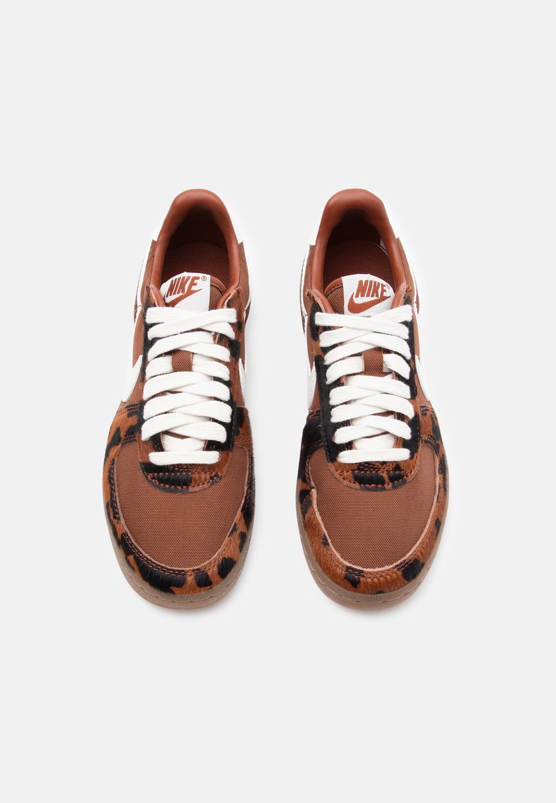 Sneakers Nike con una tomaia in tela marrone e motivo a stampa leopardata, lacci bianchi e una punta rotonda con una superficie texturizzata.