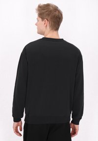Hanorac negru cu mâneci lungi, guler rotund și manșete ribbed. Textură netedă, design casual, fără decorațiuni sau modele vizibile.
