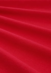 Tissu rouge avec une texture lisse, affichant un doux éclat. Le matériau semble légèrement étiré, mettant en valeur sa souplesse et la profondeur de sa couleur.