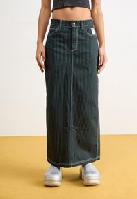 Jupe maxi en denim rayé vert avec fermeture à boutons et à zip à l'avant, présentant des coutures blanches contrastantes et deux poches latérales.