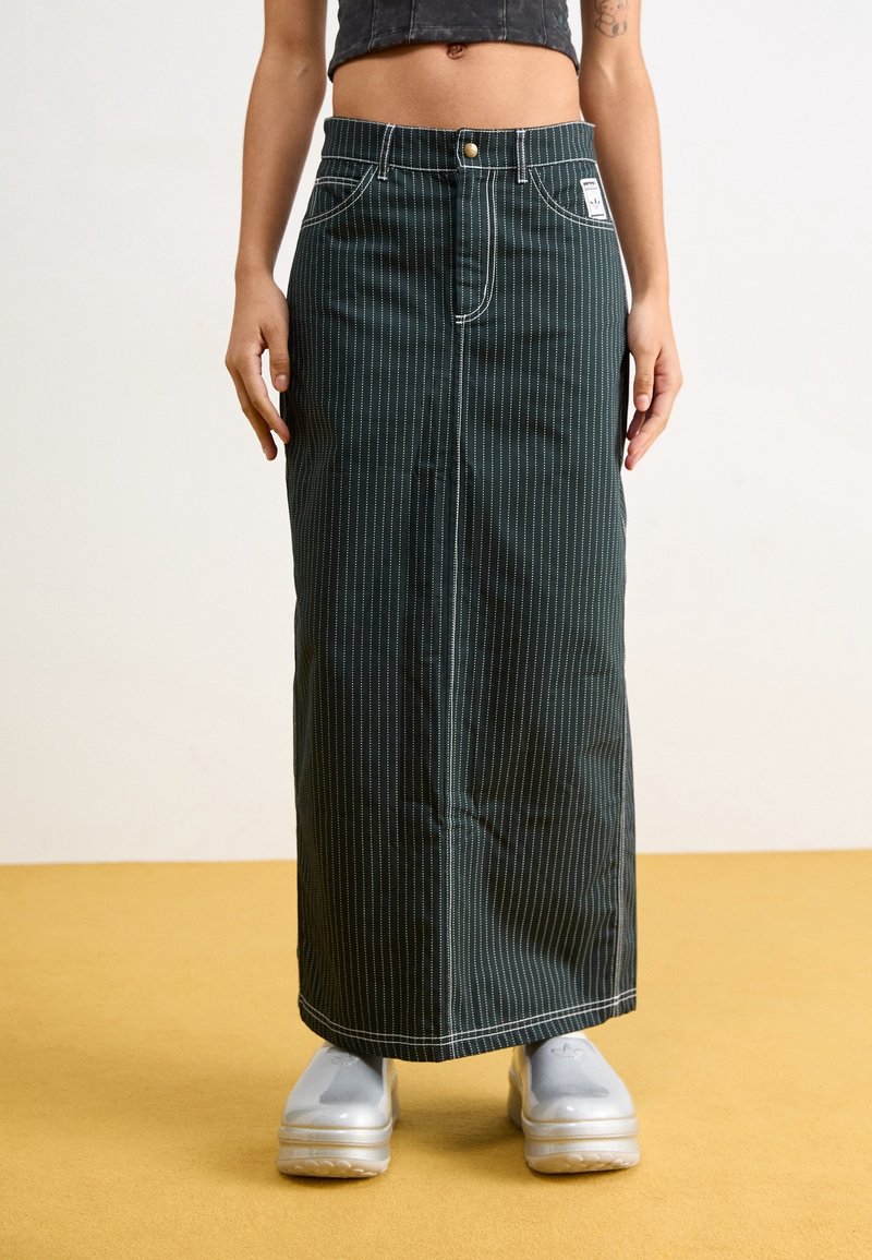 Jupe maxi en denim rayé vert avec fermeture à boutons et à zip à l'avant, présentant des coutures blanches contrastantes et deux poches latérales.