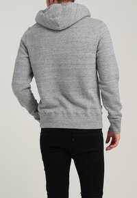 Grau Kapuzenpullover aus strukturiertem, flauschigem Stoff, mit einer geräumigen Kapuze und engen Bündchen. Die Rückansicht zeigt ein schlichtes, lässiges Design ohne Muster.