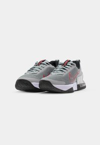 Gray athletic shoes with a mesh upper, featuring red accents and logo, black heel, cushioned sole, and textured black rubber outsole.