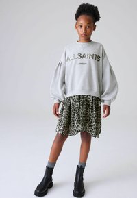 Hallide sweatpaita, millel on metallikiri "ALLSAINTS LONDON", on kombineeritud rohelise leopardimustriga kihilise seeliku ja mustade pahkluu saapadega.