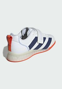 Hvid sportsko med marineblå striber, orange accenter og en tekstureret overdel. Har en Velcro-rem og en gennemsigtig gummisål.